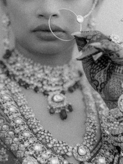 A detailed black and white shot of the bride's lips, nose ring, and henna-covered hand. This artistic photo focuses on the textures and traditions of the bridal look.