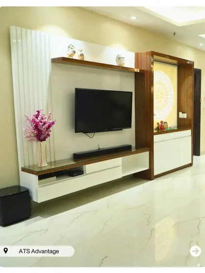 A beautiful TV unit that integrates a pooja space. The design uses white and wood tones with vertical fluting for a clean, modern aesthetic that is also practical.