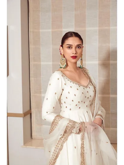 An elegant white Anarkali-style outfit by Jigar Mali. The clean lines, deep back, and delicate gold embroidery make it a timeless and graceful choice for any formal occasion.