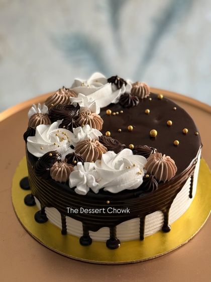A beautiful chocolate drip cake with a mix of chocolate and vanilla cream swirls on top.