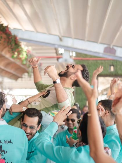 The groom is lifted onto his friends' shoulders in a moment of high-energy celebration during the baraat.