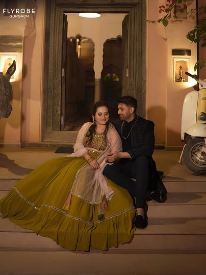 Planning a romantic evening shoot? This couple nailed the vibe. Her olive green gown with a sheer cape pairs beautifully with his dark, tailored bandhgala for a look that is both elegant and modern.
