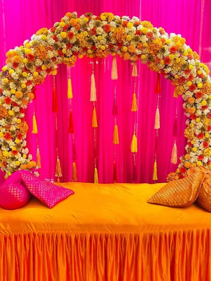 This is a simple yet beautiful seating arrangement for a Haldi ceremony. I created a floral arch with hanging tassels against a bright pink backdrop, providing a perfect spot for the bride or for guest photos.