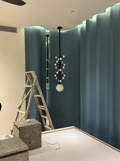 The same custom light fixture, seen from a different angle. The ladder and unfinished floor show the reality of a site in progress.