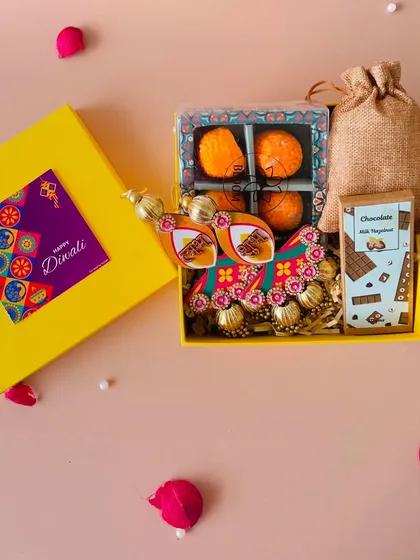 A top-down view of the yellow Diwali box with its lid next to it. The vibrant color and festive contents make it a perfect gift.