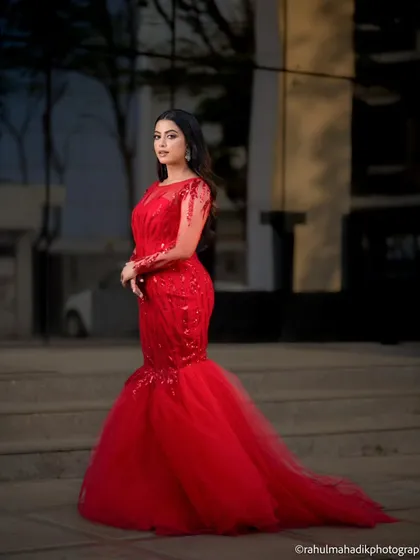 An outdoor shot of the woman in the red gown, posed on a grand staircase. The evening light and architectural elements add a sense of drama and sophistication to the portrait.