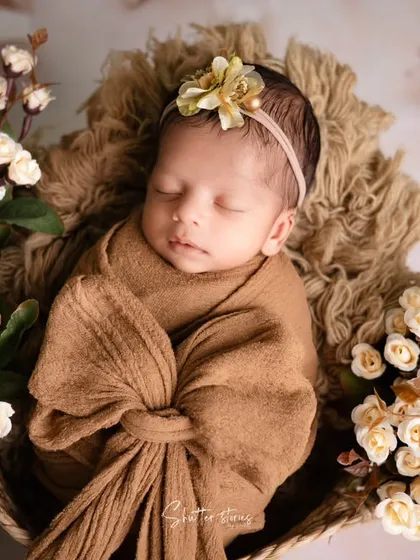 A wider view of the earthy-toned setup, incorporating off-white flowers that complement the brown wrap and textured fur.