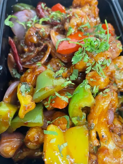 This is my Gobhi Manchurian, packed and ready to go. You can see the crispy cauliflower florets coated in a tangy sauce with colourful bell peppers and onions, garnished with fresh coriander.