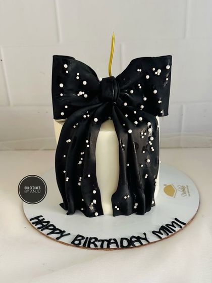 A chic and simple cake featuring a large, dramatic black fondant bow sprinkled with sugar pearls.