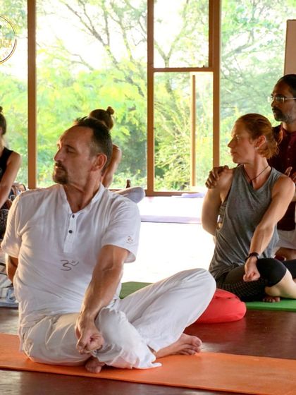 A teacher offers a verbal and physical cue to a student in a seated twist. We teach various adjustment techniques, empowering our future teachers to cater to the individual needs and preferences of their own students.