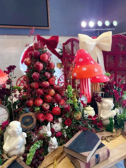 Another angle of the detailed tablescape, showing the mix of textures with apples, flowers, books, and character figurines.