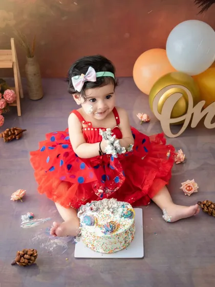 With frosting on her hands and a smile on her face, this one-year-old is having the time of her life at her cake smash session.
