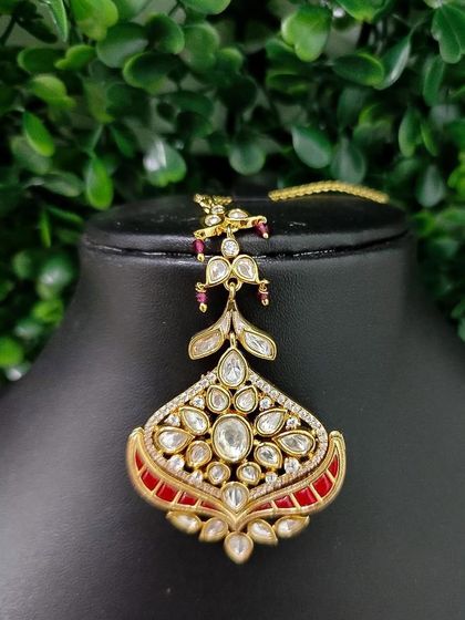 A delicate kundan maang tikka with red enamel accents.