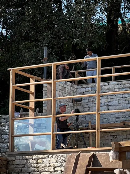 Photographer Ariel Huber sets up a shot within the timber frame of a guesthouse. Documenting the process is key to sharing the story of how these complex buildings come together in such a stunning environment.