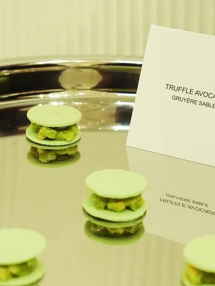 Savory truffle avocado macarons in a pale green, created for the Versace event. This dish showcases our ability to use color matching to visually integrate the menu with the brand's aesthetic.
