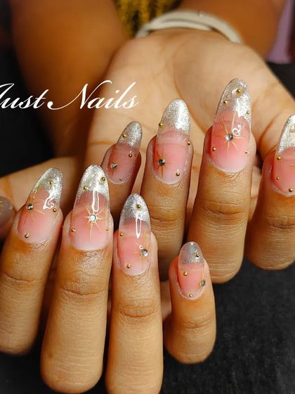 A full view of the ethereal star-dusted nails, with a sheer pink base, silver glitter tips, and gold bead embellishments.
