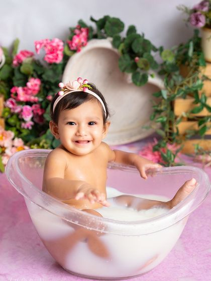 A priceless expression of pure happiness in a pink floral milk bath. Her smile is absolutely infectious and lights up the entire photo.