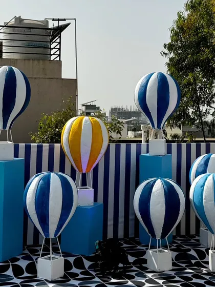 An outdoor installation of miniature hot air balloon props in blue, white, and yellow. This creative display added a touch of wonder and served as a unique photo opportunity for the kite festival.