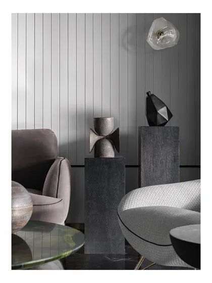 Details from our 'Reflections' project, a sea-facing apartment. We curated sculptural objects and placed them on dark pedestals against a vertically panelled wall. This creates interesting focal points and conversation starters, playing with form and texture in a monochromatic scheme.
