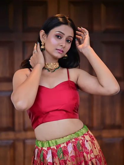A model in a red crop top and printed skirt.
