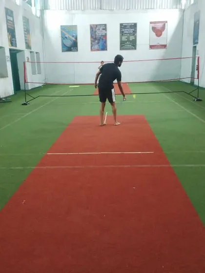Never giving up on badminton. A player picking up a shuttlecock, ready for the next point.