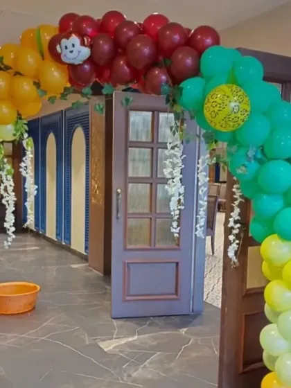 A colorful balloon arch entrance for the jungle party, with a monkey peeking out from the top.
