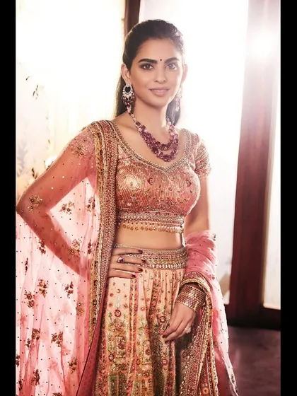 A beautiful and intricate embroidered lehenga by Tarun Tahiliani. The soft peach and pink tones, paired with a ruby necklace, create a look of sophisticated grace.