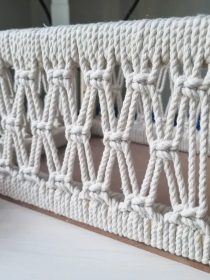 A side view of the basket, highlighting the clean lines of the wooden frame and the consistent, beautiful knot work.