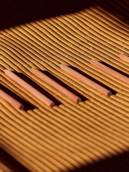 The linear, ribbed texture of our "Colonne" wallcovering creates a perfect resting place for these colored pencils, showcasing the deep grooves and tactile quality of this unique 3D design.
