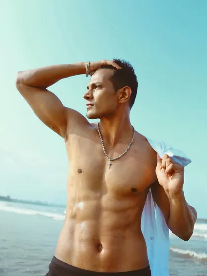 A classic male model pose against the ocean backdrop. This shot highlights the model's physique and is a staple for any fitness or fashion portfolio.