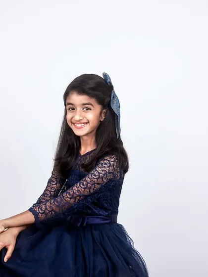 A beautiful, classic portrait of a young girl in a blue dress, taken against a clean white studio background for a timeless look.
