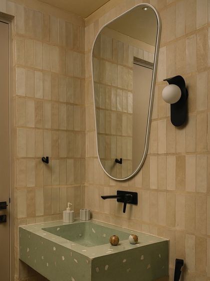 A powder room featuring a terrazzo sink and handmade tiles. This space shows how we use color and material to give each bathroom a unique essence.