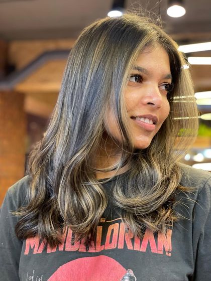 This look features a cool-toned balayage with ashy highlights. It's a modern and trendy color choice that looks great with the soft, wavy style.