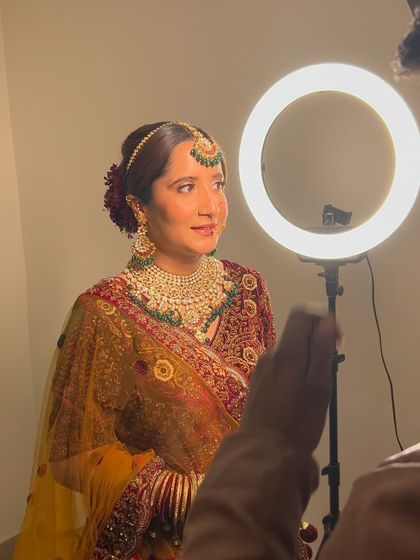 Behind the scenes with a ring light, capturing the beautiful details of this multi-colored floral bun and the bride's radiant look.