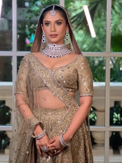 A full-length view of the modern, minimal bridal look. The makeup is elegant and understated, allowing the beautiful ivory lehenga to shine.