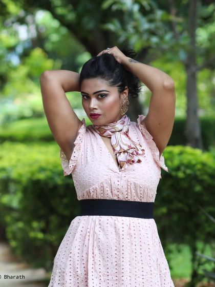 A dynamic outdoor portrait in a park, capturing a moment of movement as the subject adjusts her hair.