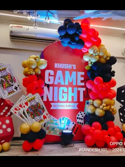 A fun "Game Night" themed birthday party. The setup features a custom backdrop and props like giant playing cards and dice made from balloons.