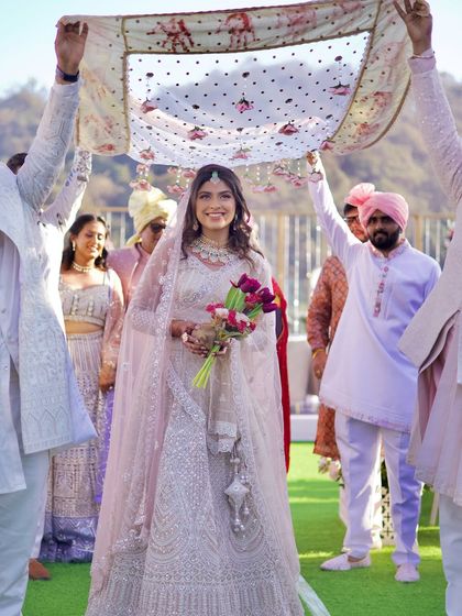 A bride making her way to the mandap under a delicate, modern 'phoolon ki chadar'. This image highlights the blend of tradition and contemporary style in today's weddings.