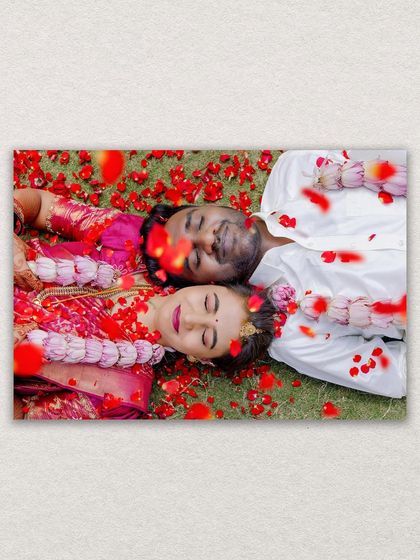 A creative overhead shot of the bride and groom lying on the grass, showered with red rose petals after their ceremony. A truly romantic final shot.