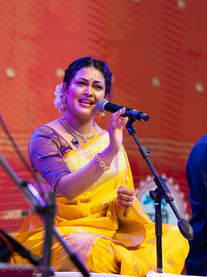 A full-seated view of Priyanka Barve during her Diwali concert, showing the beautiful drape of the Banarsi saree.