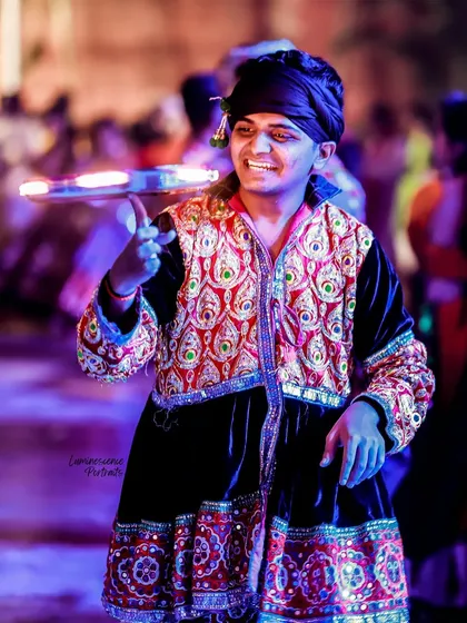 A male dancer balances a tray of diyas while dancing, a skillful and devotional performance during Navratri.