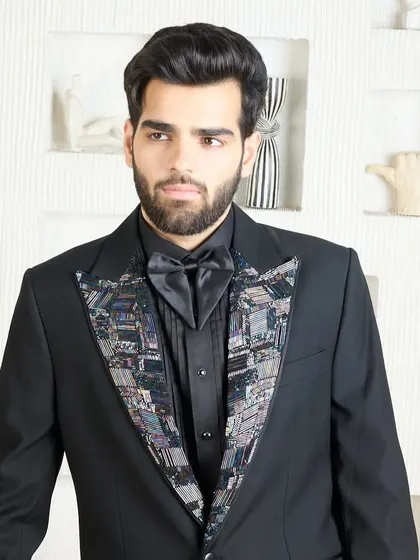 A closer look at the black tuxedo with the abstract patterned lapel, paired with a matching black shirt and bow tie for a cohesive, modern look.