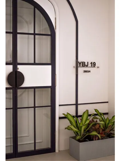 The journey begins before you even step inside. The entrance to the 'YBJ Residence' features a custom arched door with glass panels, hinting at the timeless blend of modern and classic charm within.