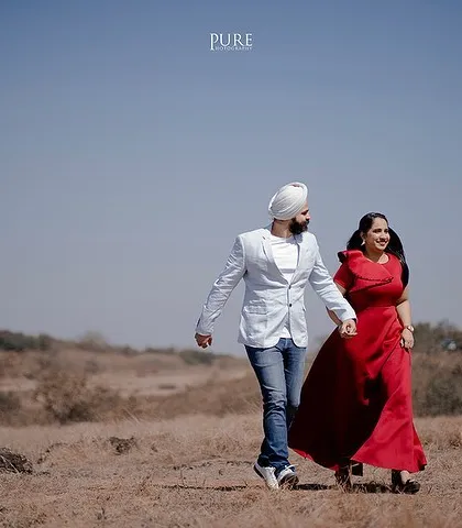Walking hand-in-hand through a wide, open field under a clear blue sky. This photo from Karan and Simarpreet's shoot feels free, happy, and full of possibility.