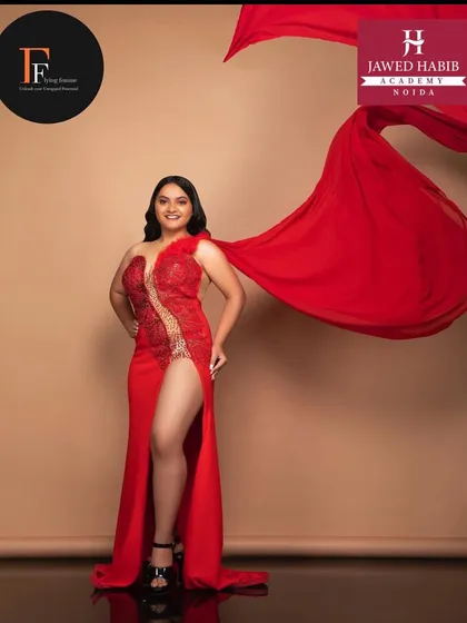 A powerful shot of a model in a red gown with a thigh high slit, her makeup and hair perfectly styled by our students for a high fashion look.