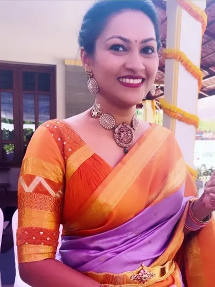 A client in a purple and orange silk saree. Her custom orange blouse features a unique design on the sleeves, blending traditional patterns with a modern cut.