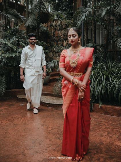 A "first look" style shot, with the groom walking towards his bride, who stands waiting with a serene expression.