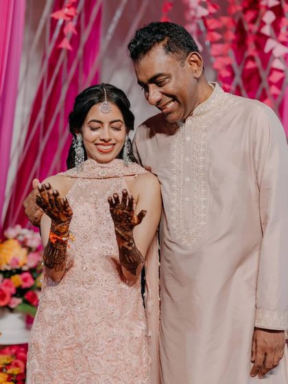 A sweet moment between the bride and her father as she shows off her intricate mehendi design. Our planning ensures you can cherish these quiet, personal moments amidst the celebration.