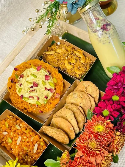 Another angle of our vibrant Holi hamper, highlighting the traditional sweets like Ghewar and Boondi, paired with Thandai and fresh flowers.