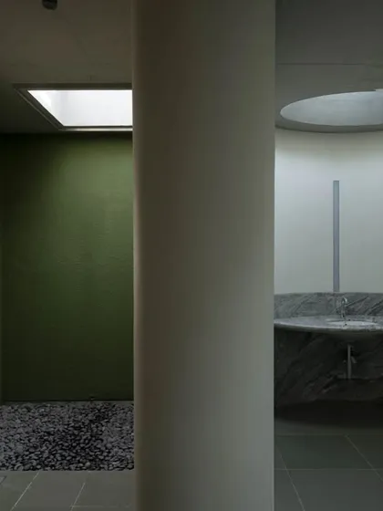 Even utilitarian spaces are considered opportunities for architectural expression. In this restroom at the Vismaya museum, a skylight illuminates a small, planted courtyard, bringing nature and daylight into a typically enclosed space.